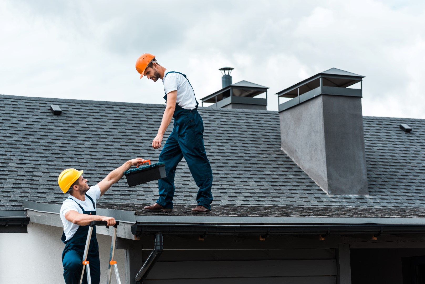 Workers climbing onto a roof with tools